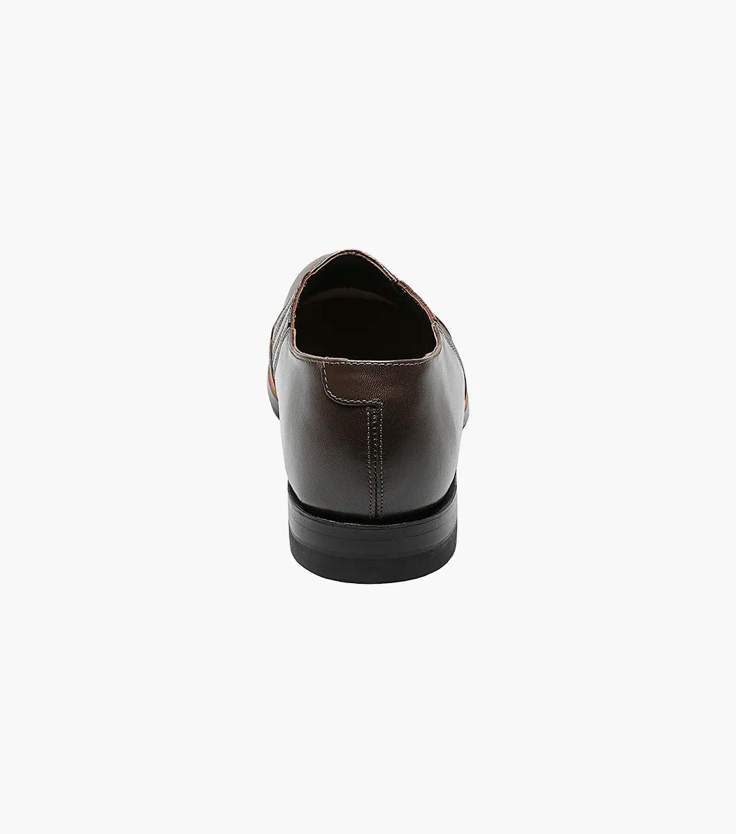 The Stacy Adams Madison Cap Toe Slip On in brown kidskin leather features an embossed pattern, elastic side panels, and a low black heel, shown as a single shoe on a white background.