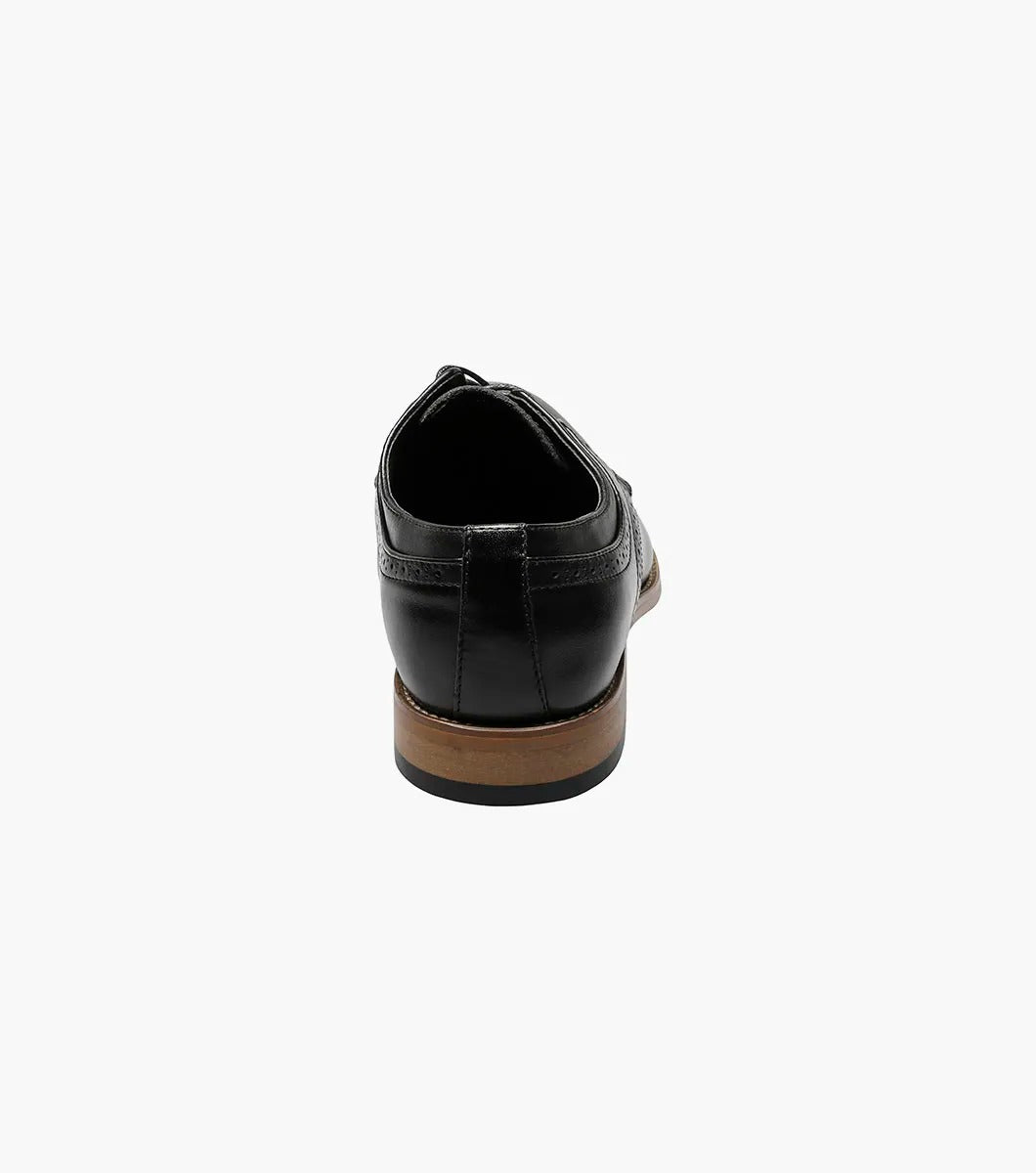 The Stacy Adams Dickinson Cap Toe Oxford (25066-001) features black leather, a brown sole, closed laces, decorative toe and side stitching, plus a cushioned insole for comfort. Shown on a plain white background.