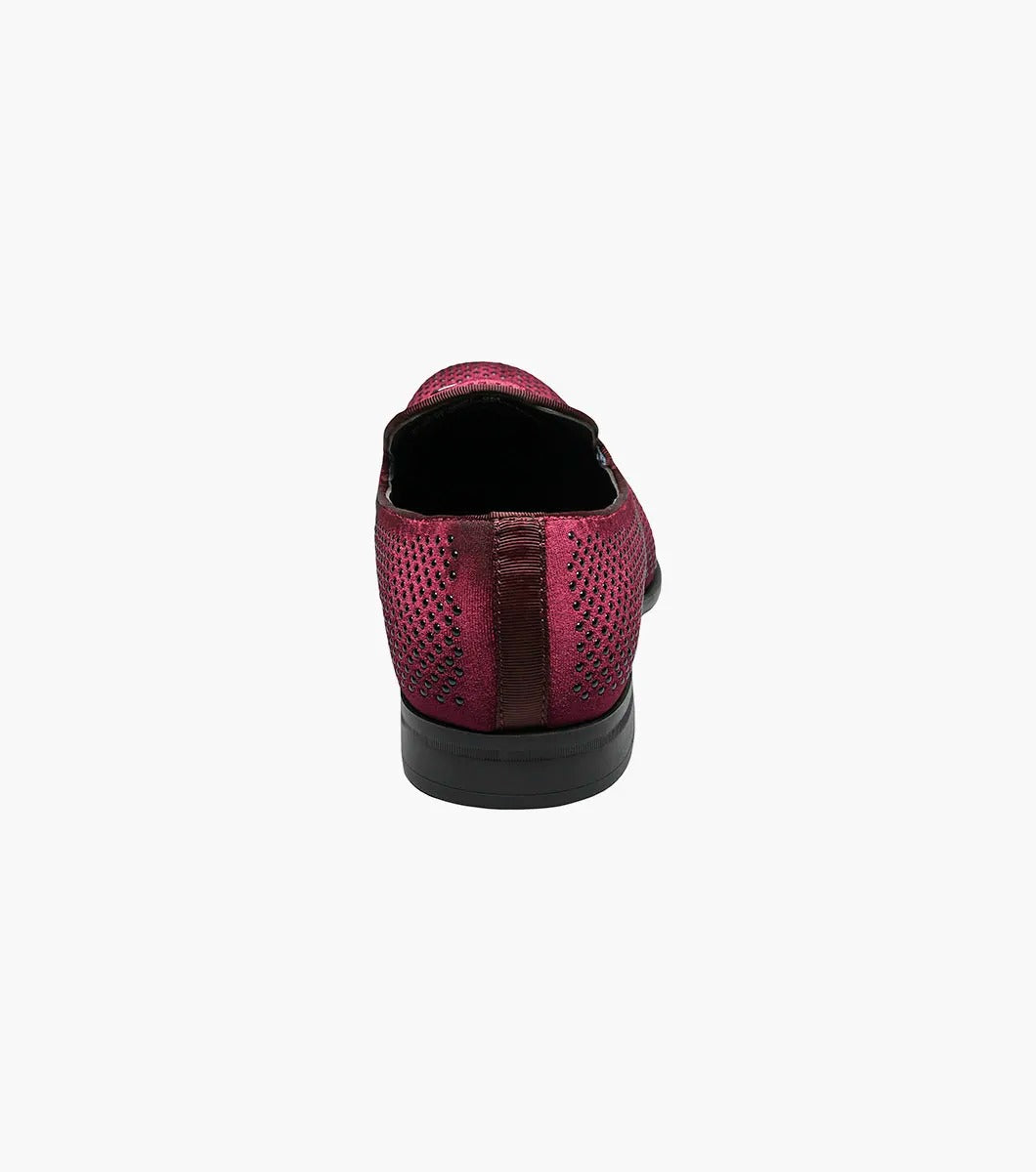 The Stacy Adams Swagger Studded Slip On in burgundy features a silver metal emblem, memory foam insole, and velvet upper, shown against a white background.