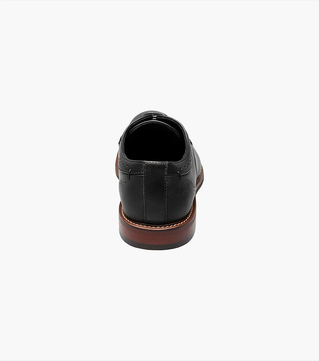 The STACY ADAMS MADDOX Cap Toe Oxford, in black and product number 25488-001, is a leather dress shoe with laces. It boasts a classic design with decorative perforations and is crafted from burnished leather for a sleek finish.