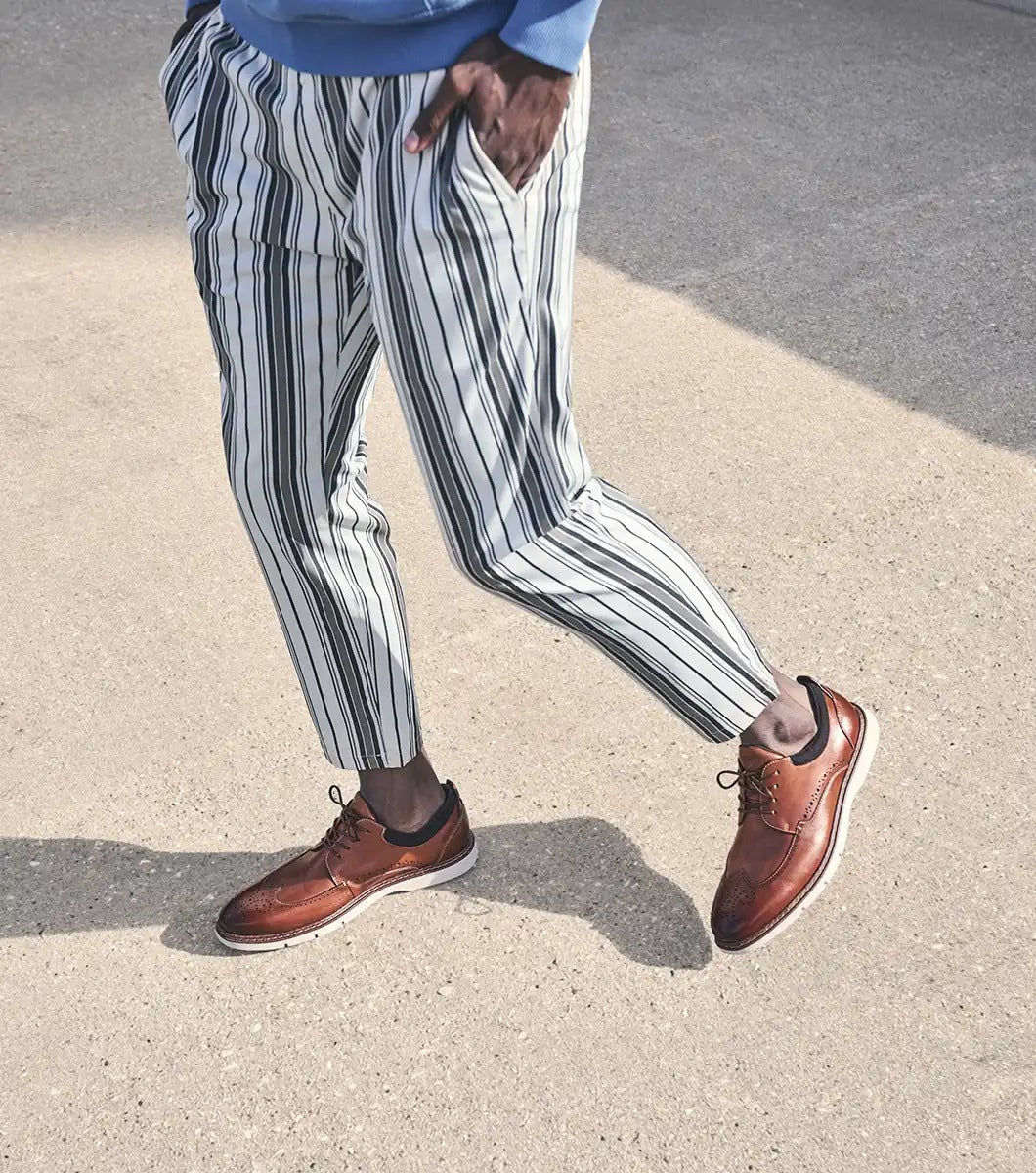 The Stacy Adams Synergy Wingtip Oxford, in Cognac color and model number 25418-221, features a brown leather brogue design complete with decorative perforations and laces. It is complemented by a contrasting white sole and enhanced by the RedZone footbed for both style and outstanding comfort.