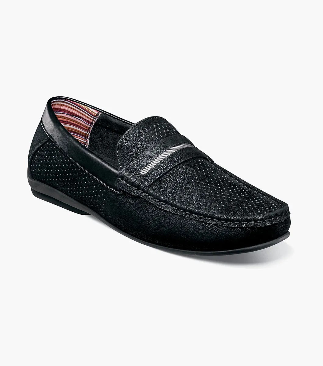 The STACY ADAMS Corby Moc Toe Saddle Slip On (Black, 25513-001) features black leather with perforated sides, a textured upper, striped band and lining, and a flat rubber sole—ideal for casual warm-weather wear.