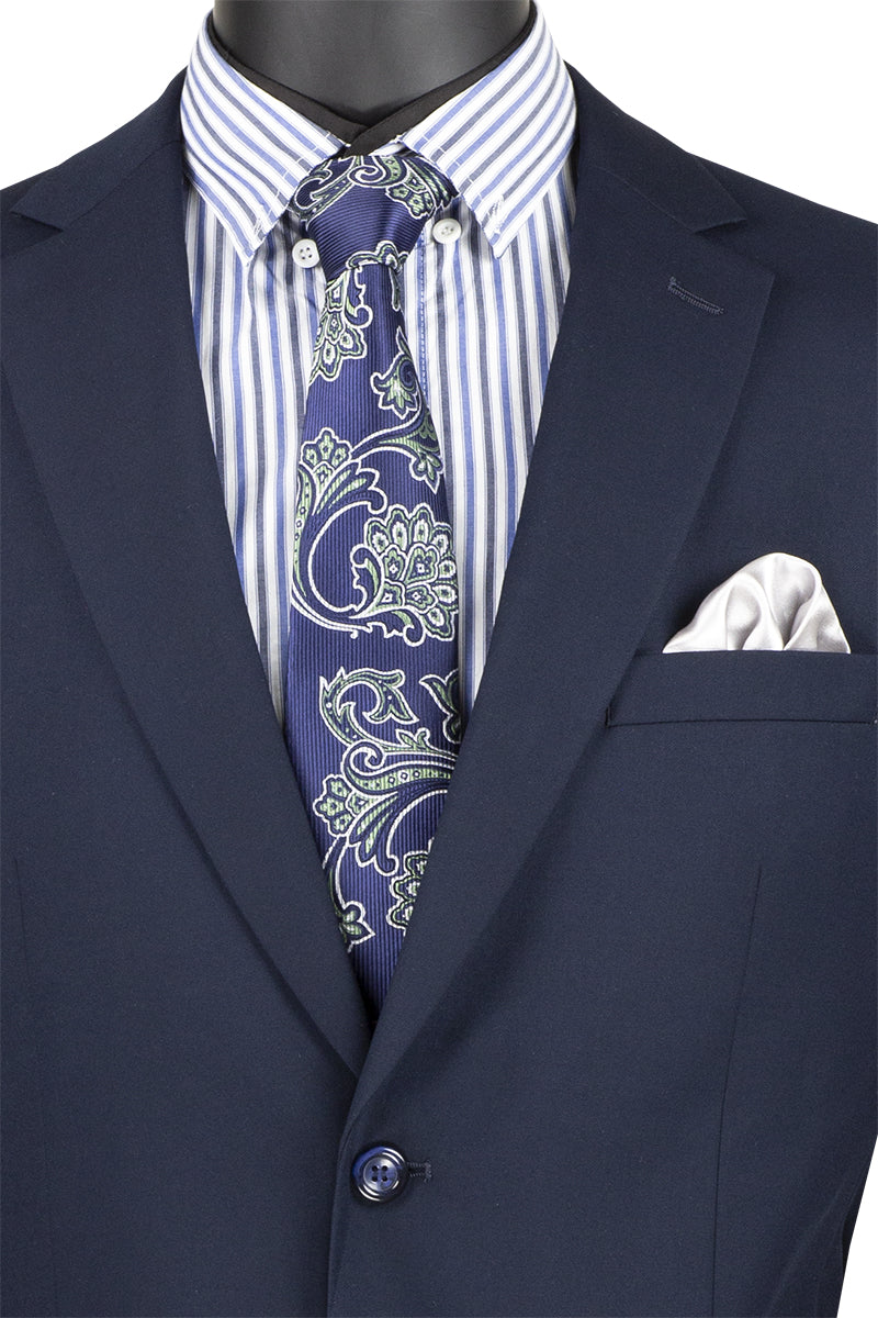 On display is a Vinci Suits 2 Piece Navy Suit (F-2C900) with a notch lapel and wool feel, elegantly paired with a blue and white striped shirt, paisley tie, and crisp white pocket square.