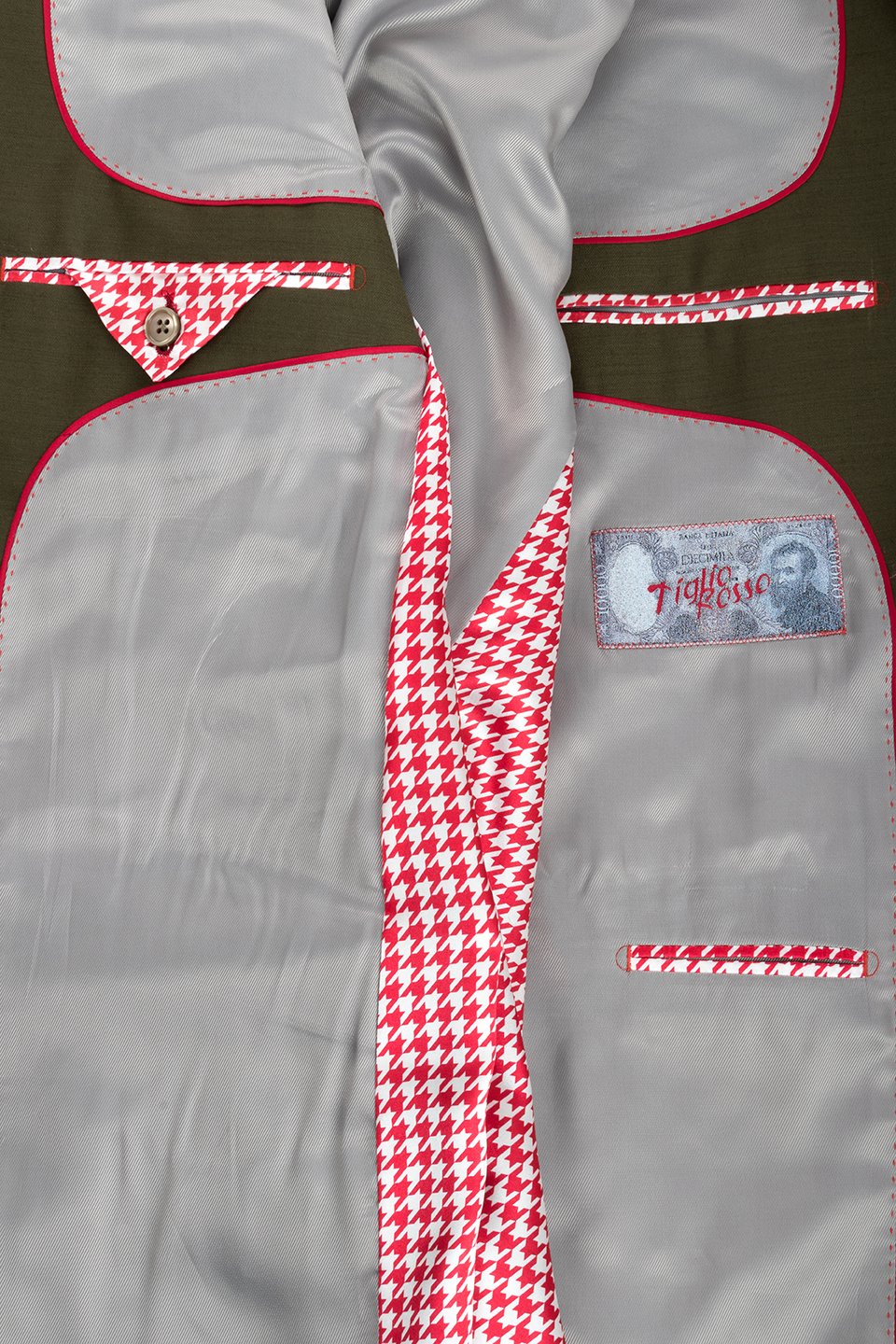 A mannequin dressed in a Tiglio Rosso San Giovesse Solid Olive suit with a patterned tie, pocket square, and flower lapel pin. The wide leg fit adds an extra touch of sophistication to this stylish ensemble.