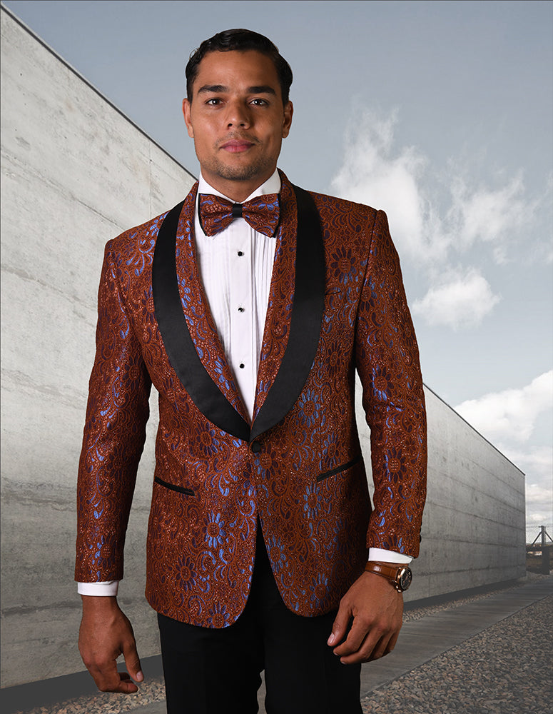 A man wearing the STATEMENT CLOTHING | LJ-105-COCO, a tailored fit patterned brown tuxedo with a black lapel and matching bow tie from Statement Clothing, stands outdoors against the backdrop of a modern concrete building.