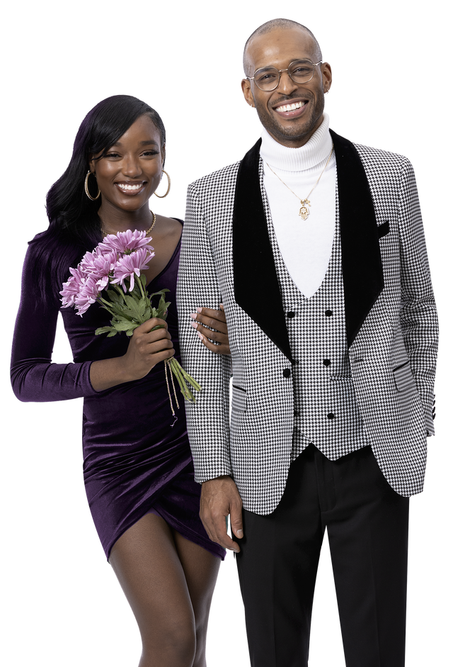 A smiling couple stands together. The woman, in a purple dress, holds pink flowers. The man exudes fashion flair in glasses and the EJ Samuel Blk/White Suit M2782, paired with a white turtleneck.