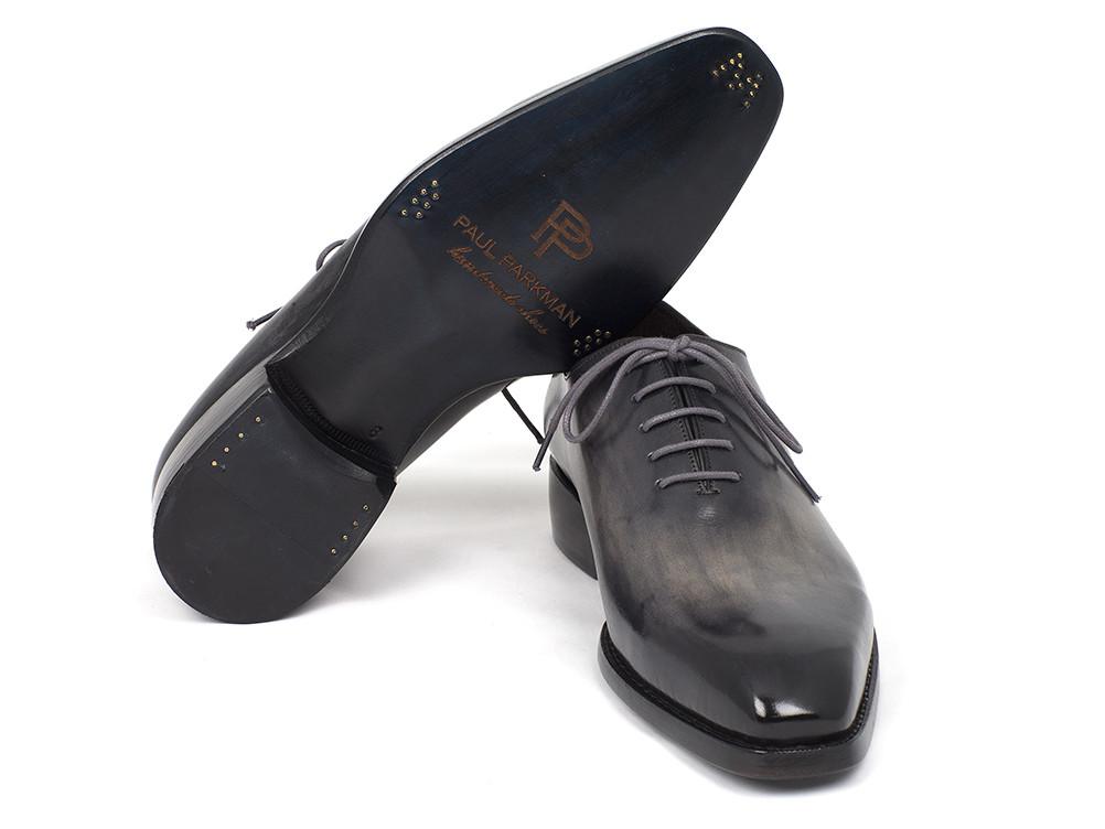 A pair of sleek Paul Parkman Goodyear Welted Wholecut Oxfords, hand-painted in glossy black and featuring gray laces, with one shoe standing upright and the other lying beside it.