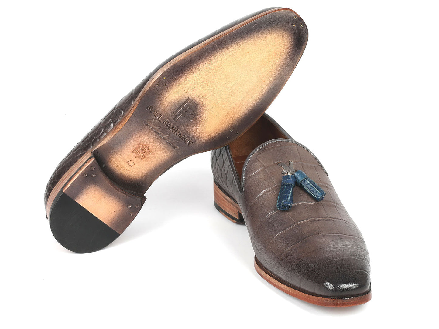 A pair of Paul Parkman Men's gray loafers crafted from crocodile-embossed calfskin and featuring distinctive tassels is gracefully showcased against a white background.