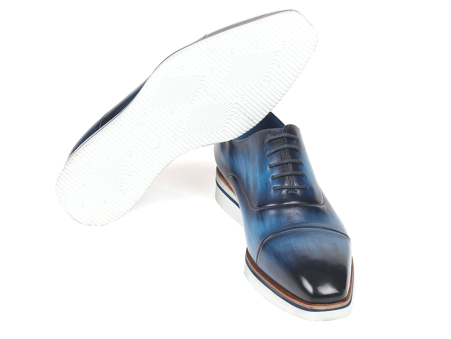 Introducing the Paul Parkman Smart Casual Oxfords in blue leather, featuring hand-painted calfskin with brown accents and white soles. These stylish shoes are arranged in a cross position and are ideal for smart casual occasions.