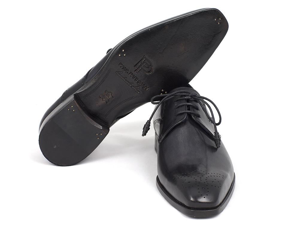 A pair of Paul Parkman Black Medallion Toe Derby Shoes - 6584-BLK, crafted from black leather with decorative stitching and a medallion toe design, complete with classic laces. One shoe leans elegantly against the other, highlighting its sophisticated style.