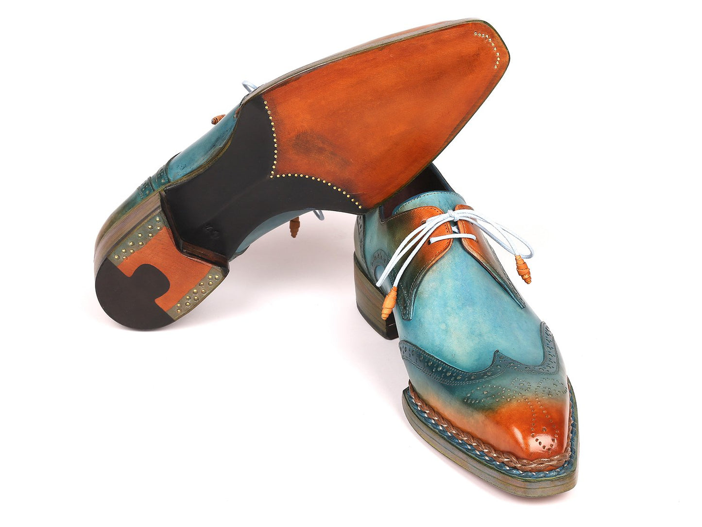 The Paul Parkman Norwegian Welted Wingtip Derby Shoes in Turquoise & Tobacco feature a vibrant leather design with gradient shades of blue, green, and orange. These shoes are adorned with white laces and decorative perforations, crafted from hand-painted leather.