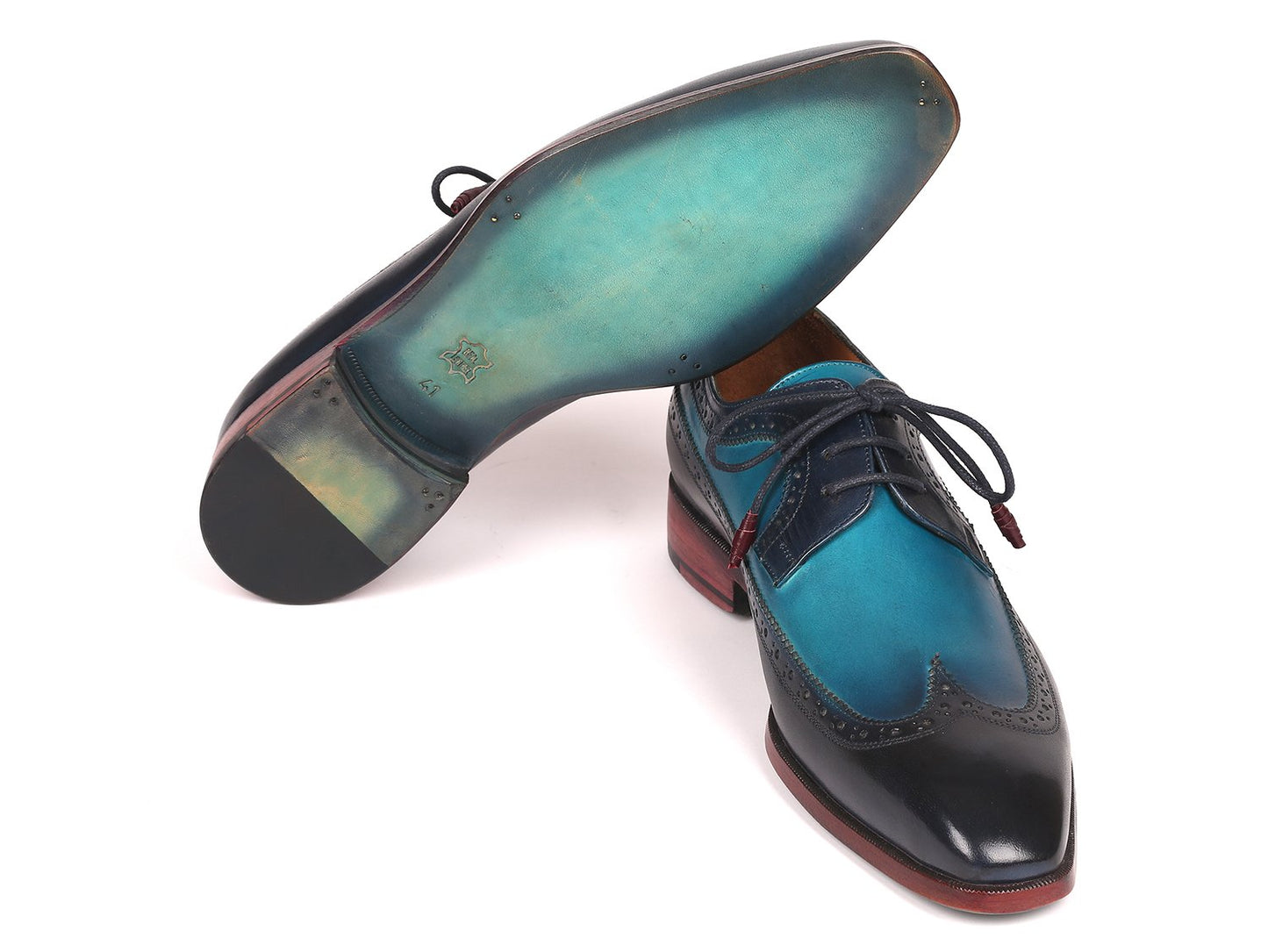 Introducing the Paul Parkman Blue Dual Tone Wingtip Derby Shoes - 6931BLU, a sophisticated pair of men's dress shoes meticulously crafted from hand-painted calfskin. These elegant shoes feature striking blue leather, contrasting black toe caps, exquisite brogue detailing, and distinctive dark red soles, making them ideal for those who value elegance with a unique flair.