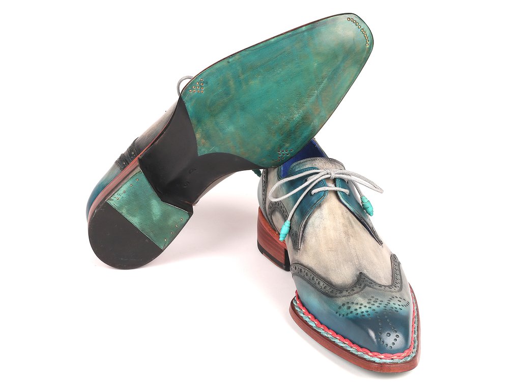 The Paul Parkman Norwegian Welted Wingtip Derby Shoes in Blue & Grey - 8506-BLU are hand-painted leather shoes featuring multicolored accents in teal, grey, and red. With decorative perforations and teal laces, these stylish shoes are showcased against a white background.