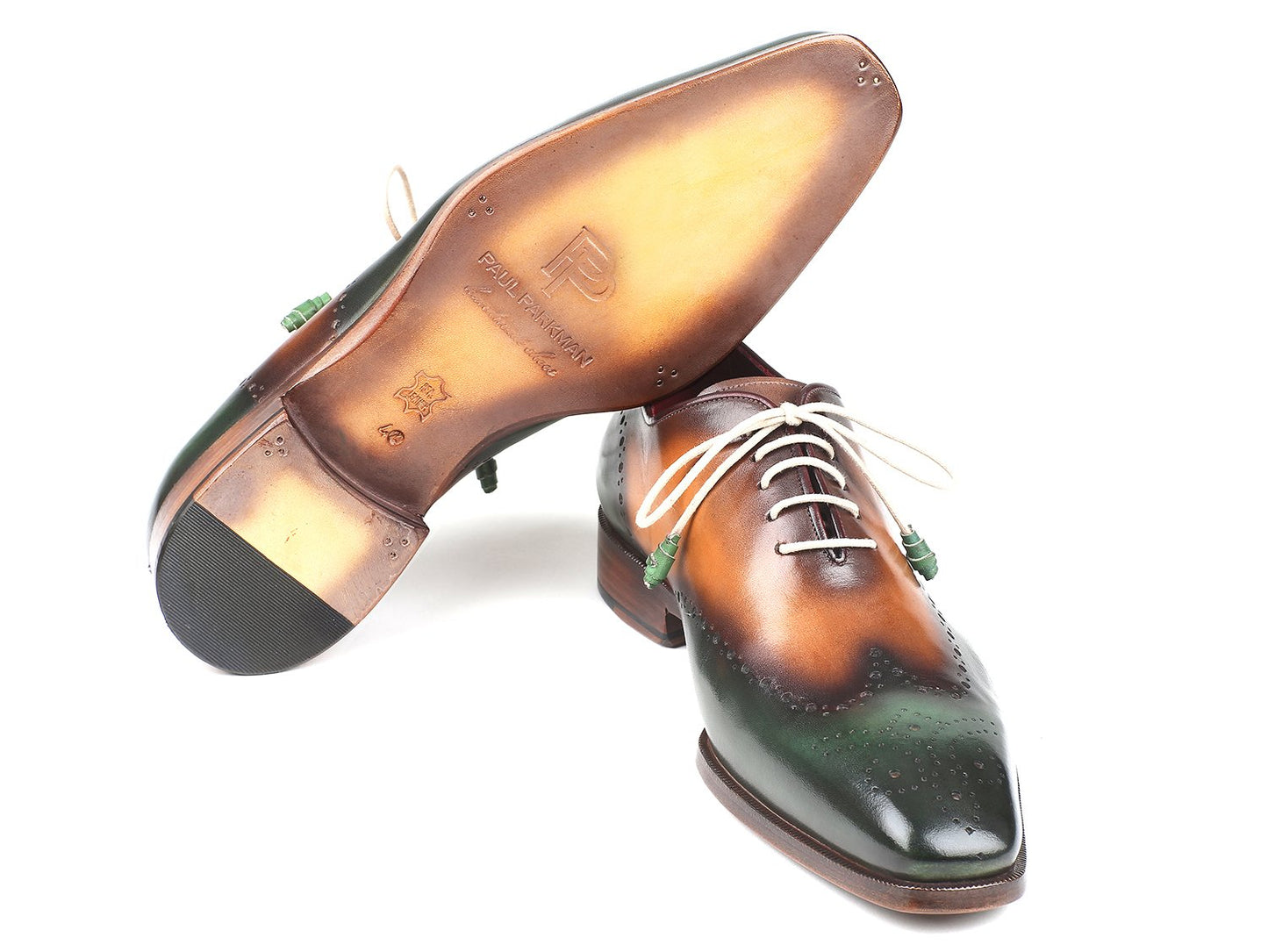 Paul Parkman presents the Green & Camel Wingtip Oxfords - 097GV22, a pair of handmade brogues crafted from hand-painted leather in green and brown, featuring white laces and intricate perforated detailing, displayed on a white background.