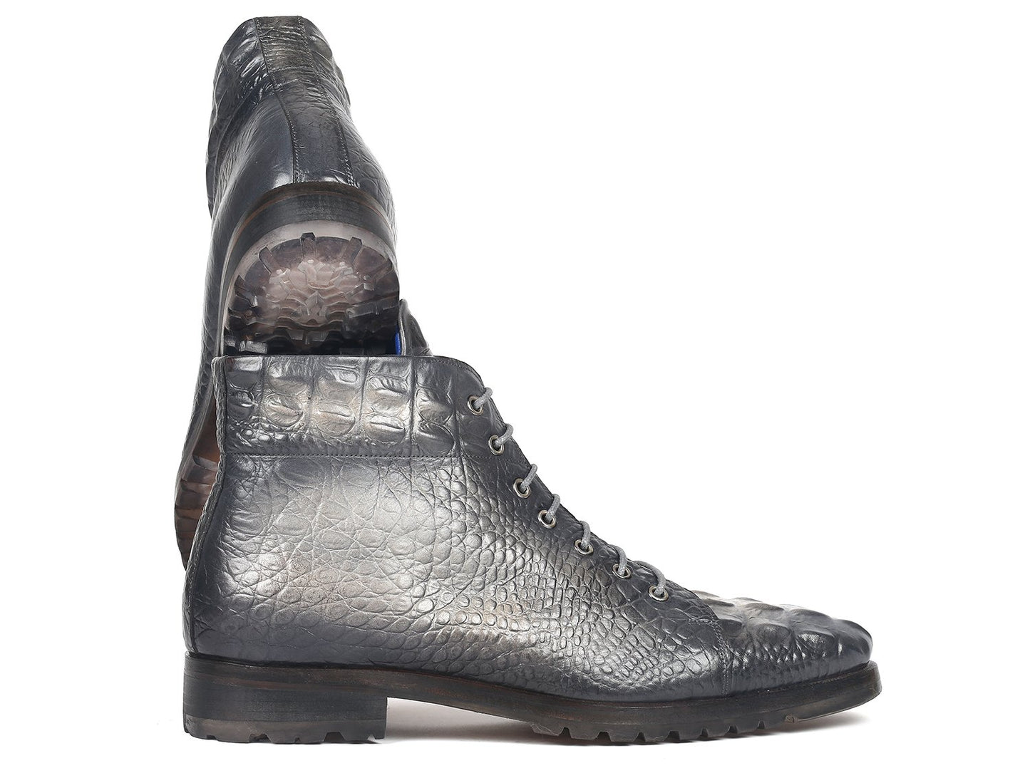 The Paul Parkman Gray Croco Embossed Leather Boots, model 12811-GRY, are exquisitely designed with hand-painted gray leather and a croco-embossed pattern. They feature lace-up fronts and sturdy soles, with one boot stylishly propped against the other.