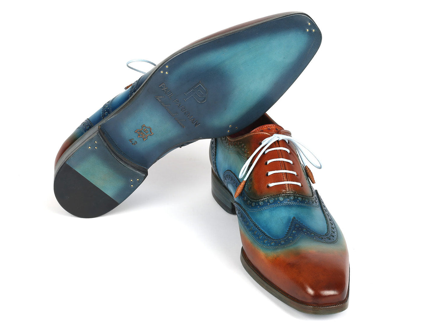 The Paul Parkman Wingtip Oxfords Turquoise & Tobacco 228-TRQ are men's dress shoes made from hand-painted leather, featuring a two-tone design in brown and blue with intricate perforations and white laces, elegantly displayed on a white background.