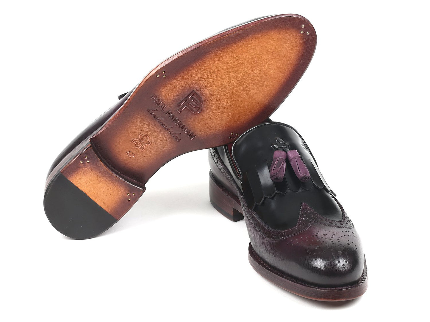 A pair of Paul Parkman Kiltie Tassel Loafers in black and purple, featuring shiny hand-painted leather with intricate brogue detailing and purple tassels, artfully placed on a white background.