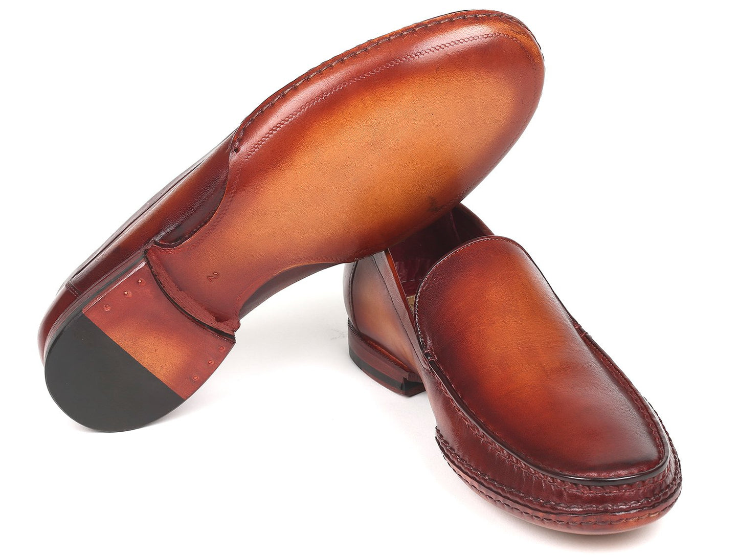 A set of Paul Parkman Hand-Sewn Moccasins in brown, created using hand-painted leather, displays one shoe slightly elevated and overlapping the other.