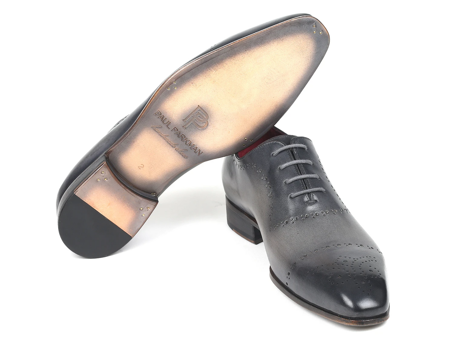 The Paul Parkman Grey Hand-Painted Classic Brogues - ZLS34GRY from Paul Parkman showcase intricate decorative perforations, a red interior lining, and a sleek leather sole, all presented against a white backdrop.