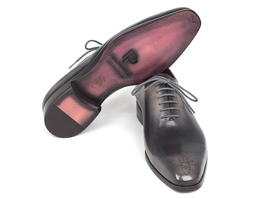The Paul Parkman Gray & Black Wholecut Oxfords (KR254GRY), with their sleek gray leather and lace-up design, feature subtle perforations on the medallion toe caps, all set against a white background.