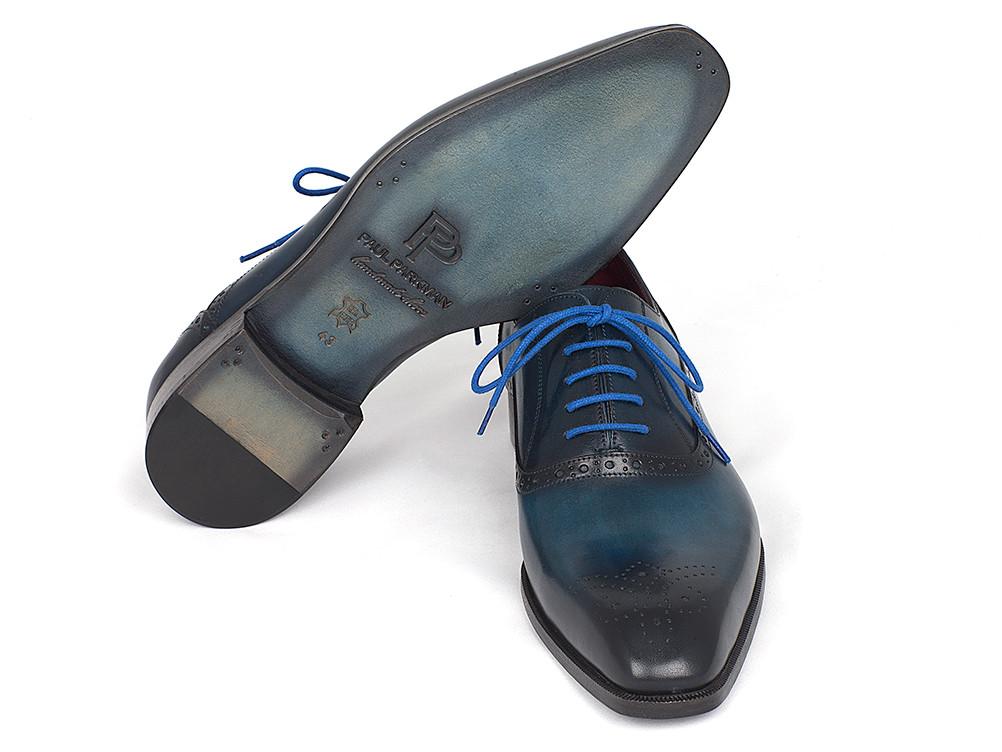 The Paul Parkman Blue & Navy Medallion Toe Oxfords – FS88VA are a striking pair of polished blue leather dress shoes with matching blue laces and decorative perforations. These handmade oxfords feature hand-painted leather and a stacked wooden heel, offering a unique touch to their timeless elegance.