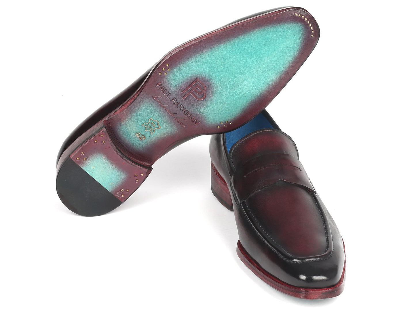 Introducing the Paul Parkman Purple Burnished Penny Loafers - 10PR23, a stunning pair of made-to-order shoes that display exquisite craftsmanship. These handcrafted loafers feature unique details like red soles and a blue interior lining, embodying luxury and sophistication.