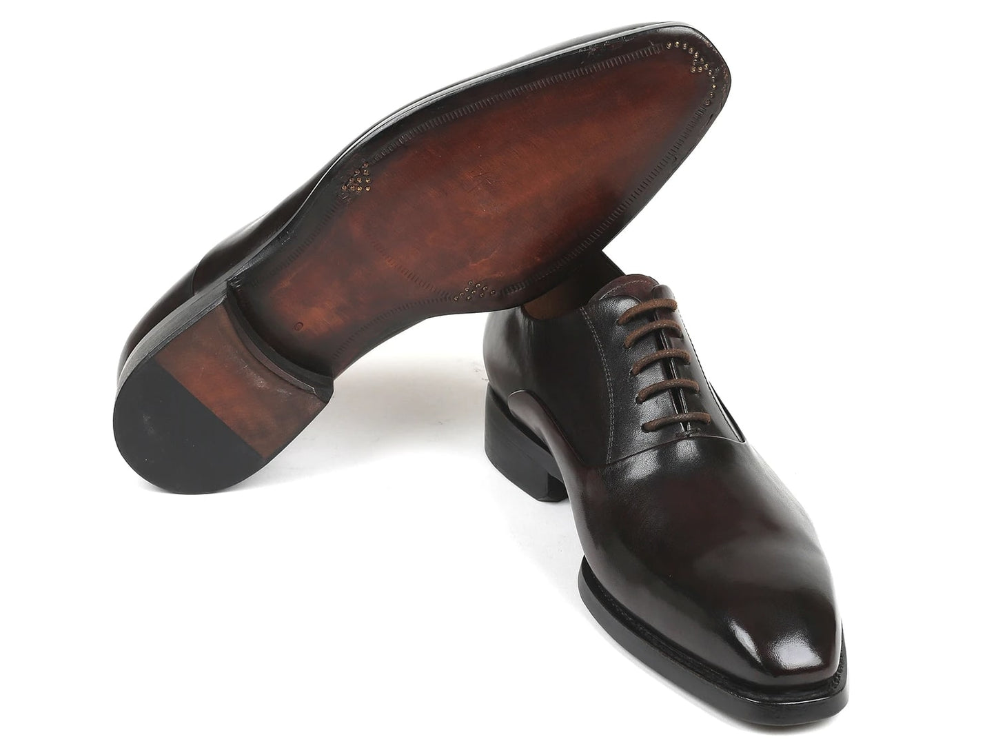 A pair of Paul Parkman Plain Toe Oxfords in brown, featuring a closed lace-up design, meticulously crafted from hand-painted leather, with one shoe slightly elevated above the other.