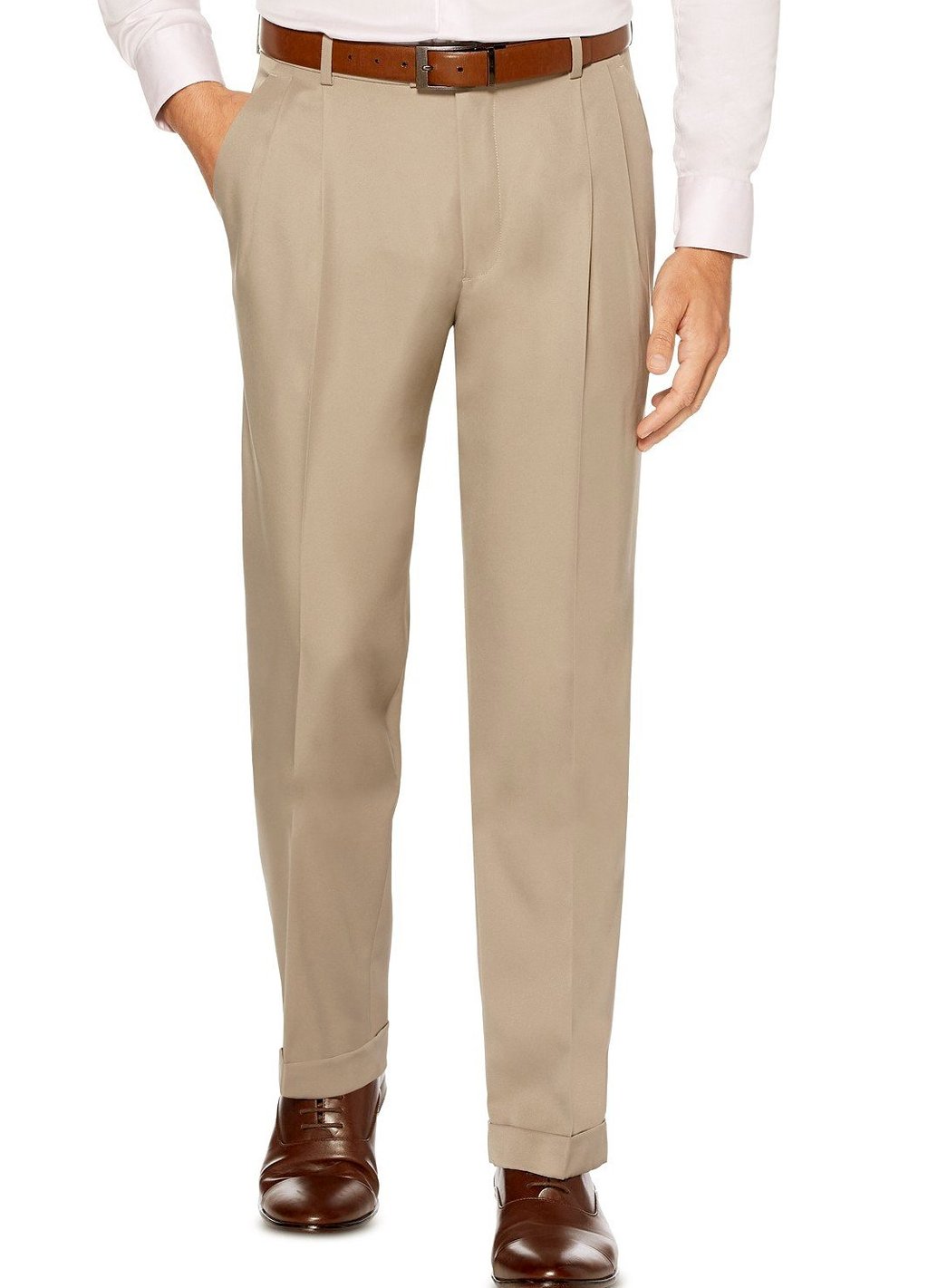 A man wearing Vinci Suits' Regular Leg Pleated Pre-Hemmed With Cuffs Dress Pants in khaki pairs them with brown shoes and a crisp white shirt, standing with one hand in his pocket.