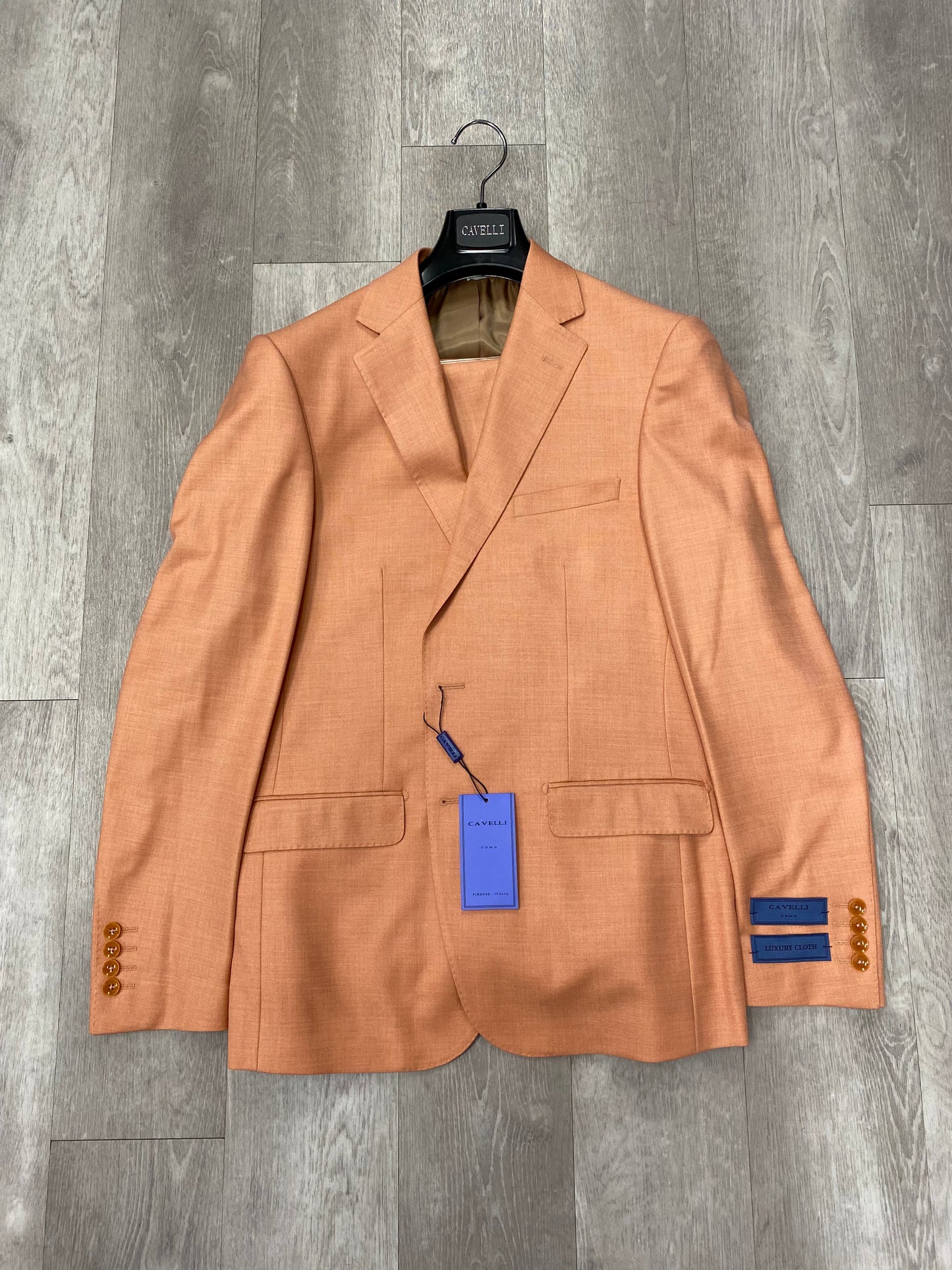 A Cavelli Uomo Porto SLIM FIT Suit Jacket in orange by CAVELLI, displayed on a hanger over a gray wood floor with tags attached. FINAL SALE: No return or exchange.