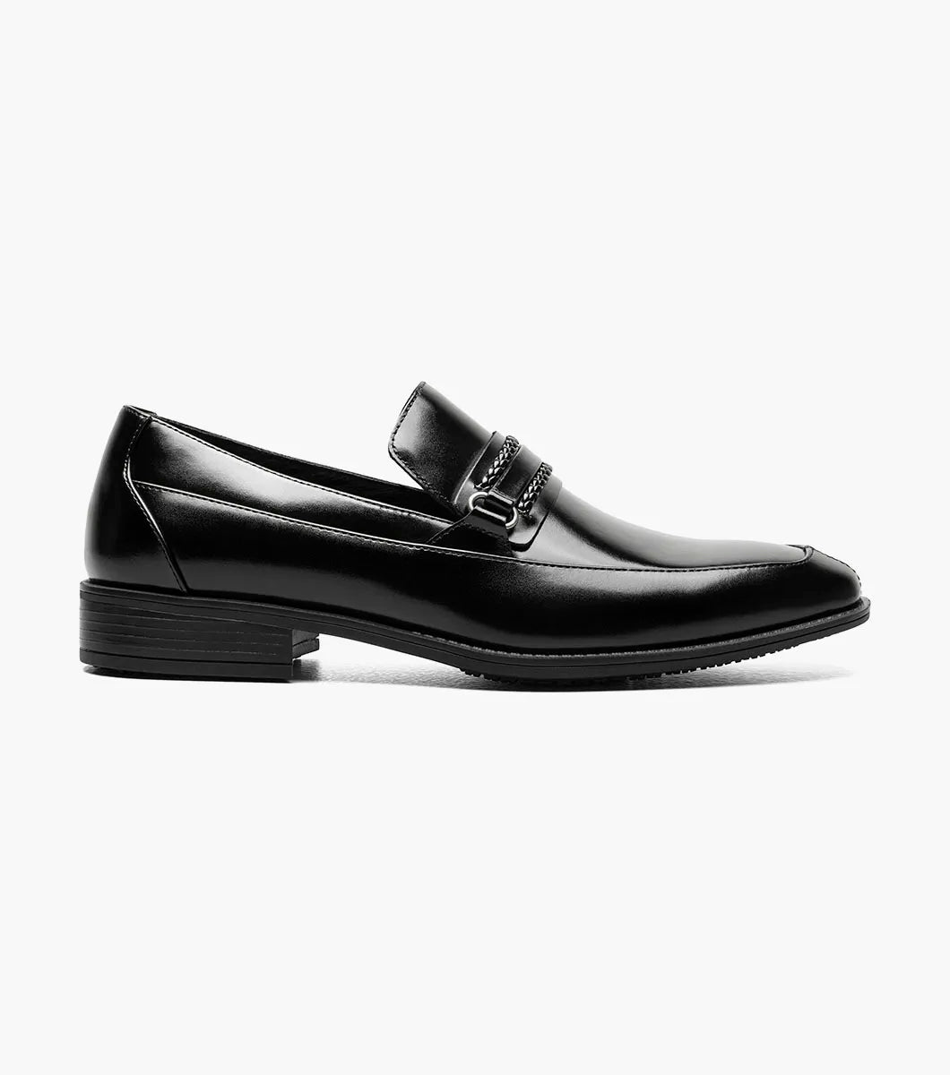 The Stacy Adams Aberdeen Moc Toe Saddle Slip On (20203-001) is a black dress loafer with a leather upper, low heel, square toe, and braided strap detail across the upper.