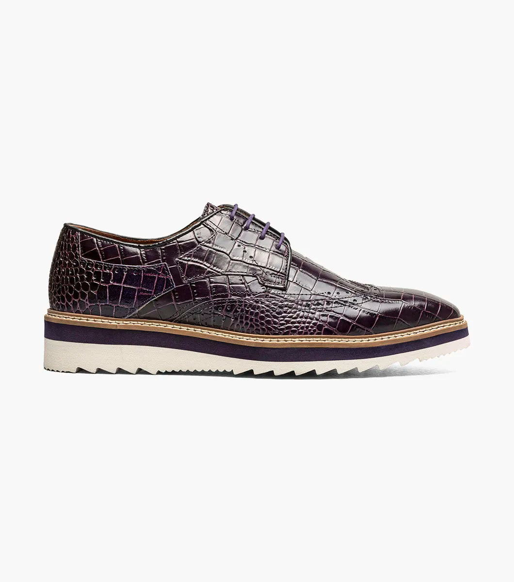 The Stacy Adams Alario Wingtip Oxford in purple (25725-542) features crocodile print leather, a lace-up design, contrasting sole, and textured outsole, shown on a white background.