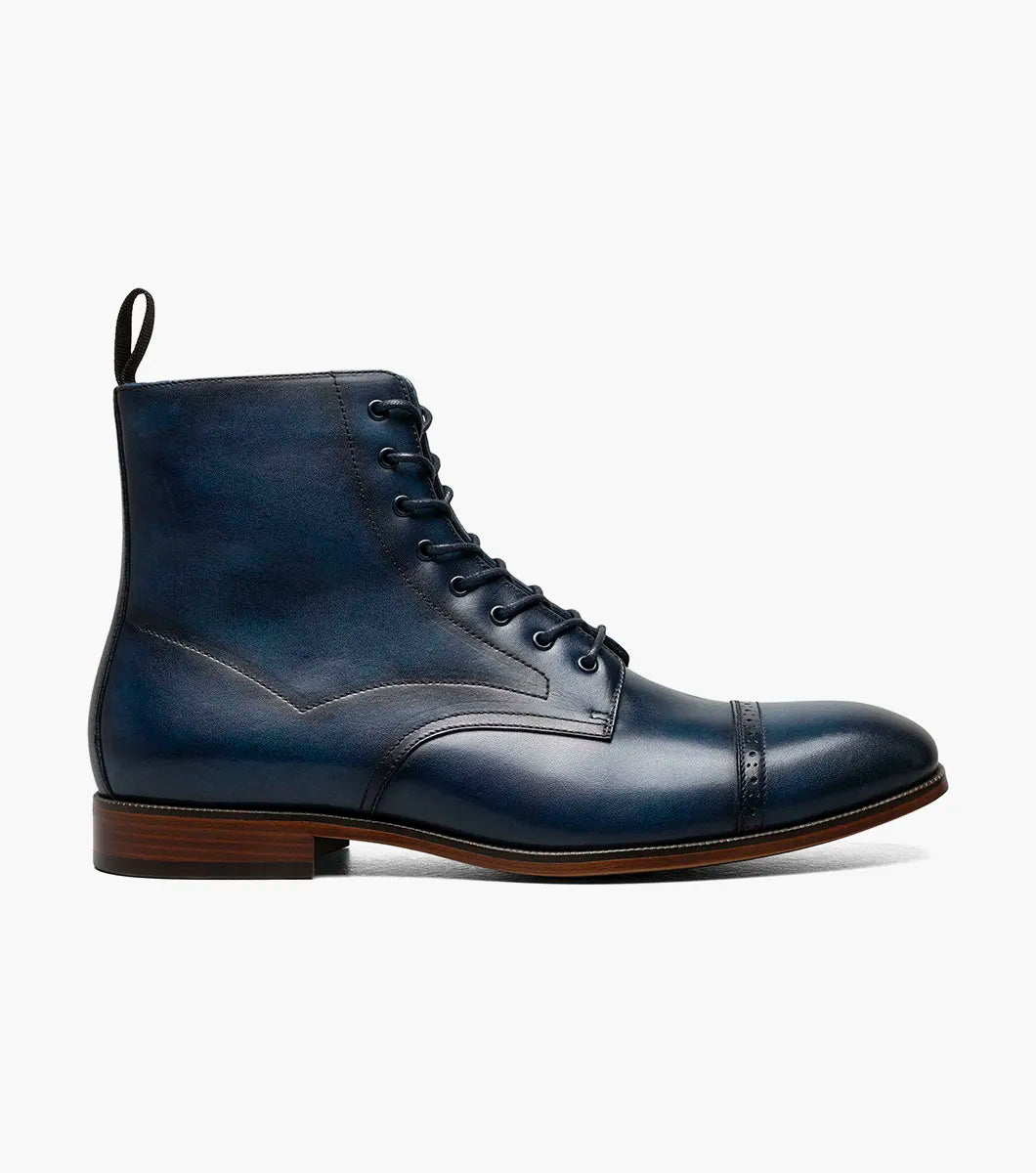 The Stacy Adams Henry Cap Toe Lace Up Boot (Navy, 25718-410) features a dark blue leather upper, cap toe, brown sole, and black heel tab. Shown in side profile on a white background.