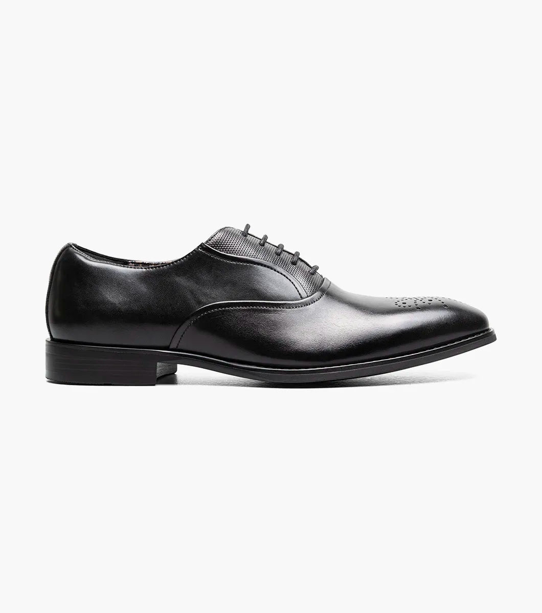 The STACY ADAMS Langford Plain Toe Oxford in black (25795-001) is a classic leather dress shoe featuring perforated toe detailing and black laces, designed to provide both style and comfort for any formal occasion. Shown on a white background.