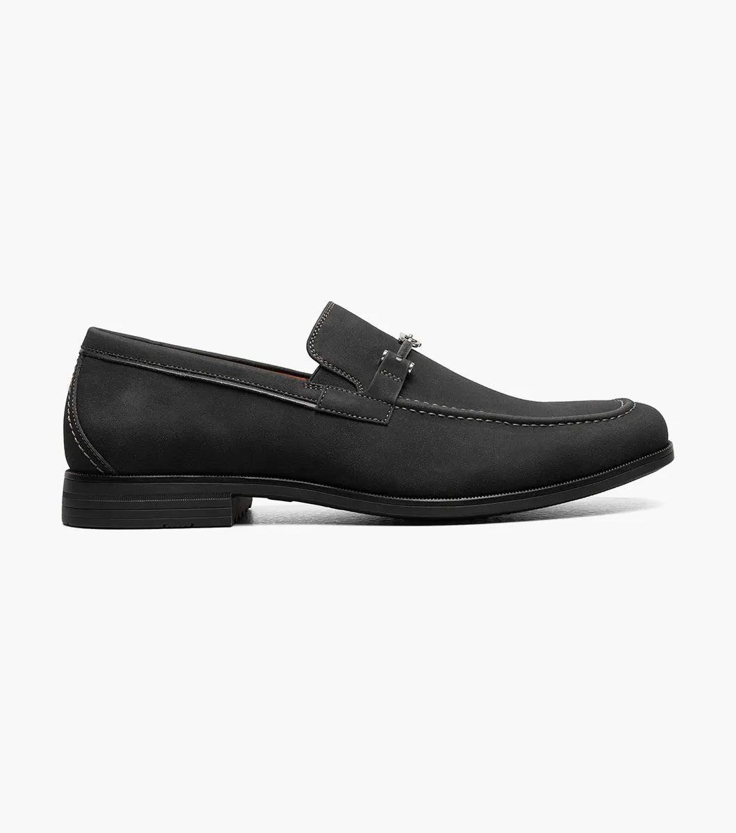 The STACY ADAMS Richardson Moc Toe Bit Slip On (25746-001) features black suede, white stitching, a metal bit detail, low heel, and cushioned RedZone footbed—all shown on a plain white background.