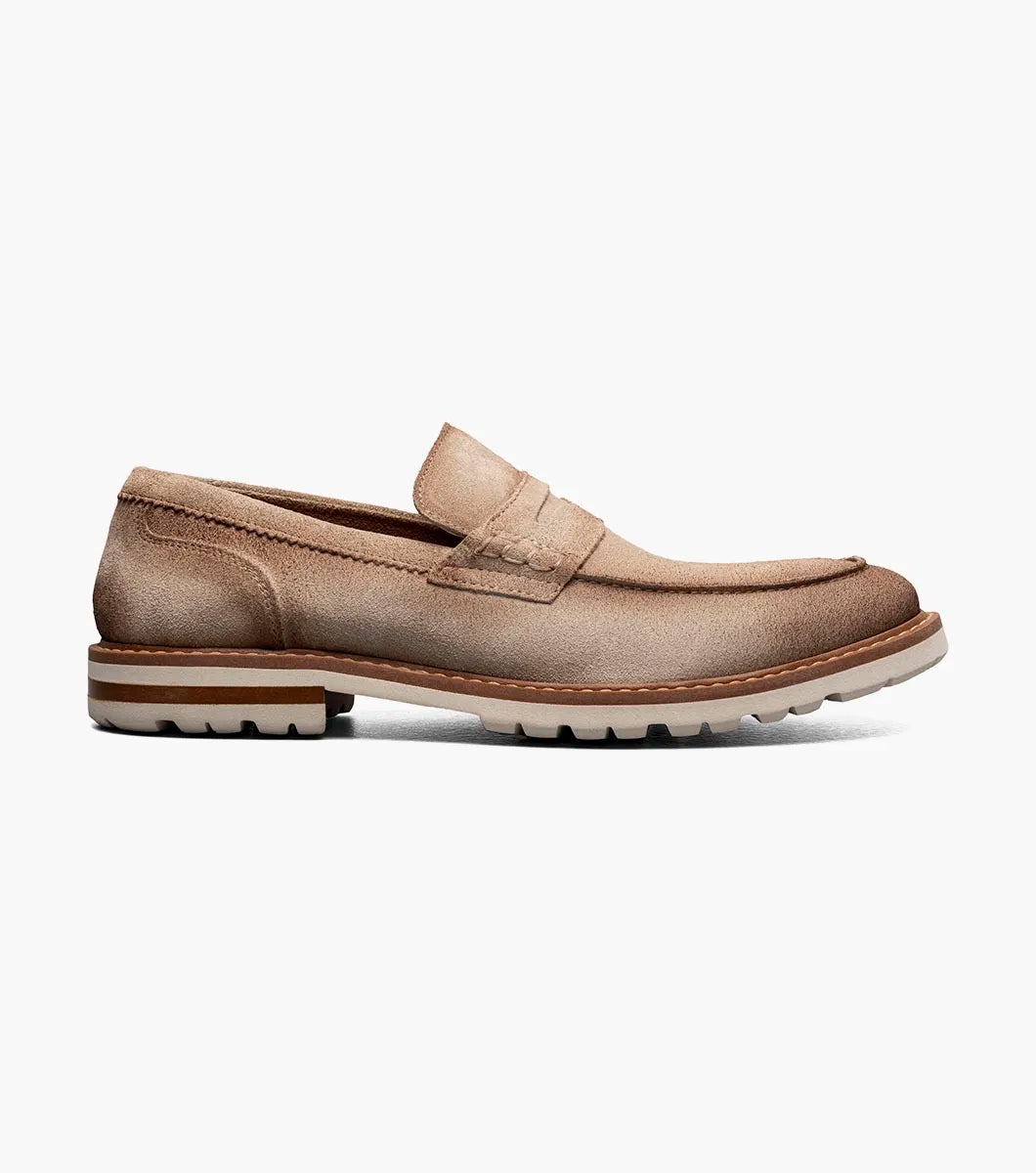 The STACY ADAMS Hopkins Moc Toe Penny Slip On in Sand (25708-269) is a light brown suede loafer with a white and tan rubber sole and red interior lining, shown on a white background.