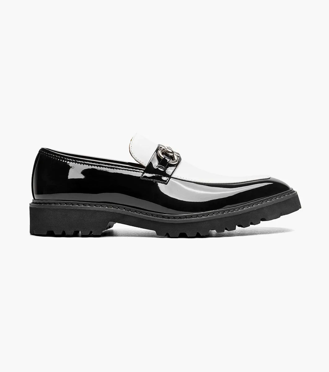 The Stacy Adams Carabello Moc Toe Bit Slip On in Black with White (25804-111) by STACY ADAMS is a black and white loafer featuring a chunky sole, metallic chain detail on the upper, and a comfortable memory foam insole, displayed on a white background.