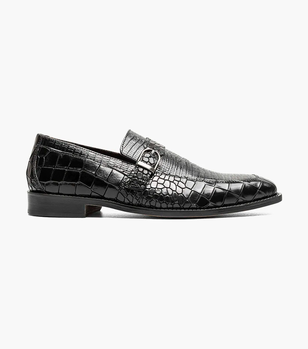 The Stacy Adams Rubiano Moc Toe Buckle Strap Slip On in black (style 25787-001) by STACY ADAMS features a black crocodile print leather pattern, a silver buckle strap slip-on design, and a low heel, displayed on a plain white background.