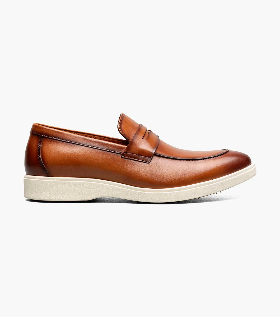 The Stacy Adams Spencer Moc Toe Penny Slip On (Tan, style 25673-240) is a men's dress shoe with a classic loafer design, white rubber sole, and brown leather upper, shown on a plain white background.