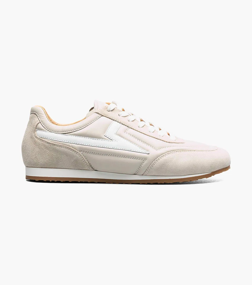 The STACY ADAMS Stacy Adams - Action 150 Sporty Lace Up in Cream (25797-113) is a beige and white low-top modern sneaker with a cushioned footbed, featuring white laces, sleek white side detailing, and a tan rubber sole, photographed on a white background.