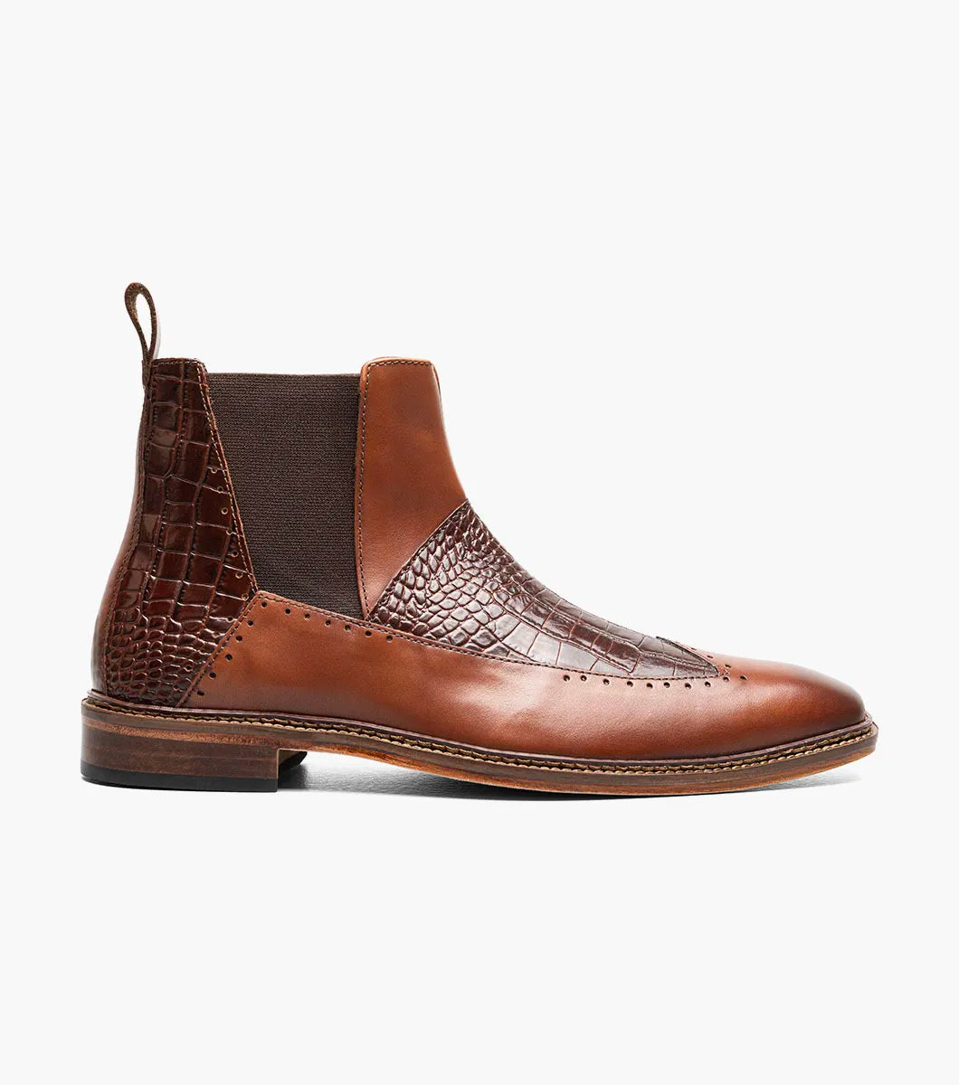The Stacy Adams Garza Wingtip Chelsea Boot in Cognac features crocodile texture detail, elastic side panel, heel pull tab, cushioned footbed for comfort, and a low wooden sole.