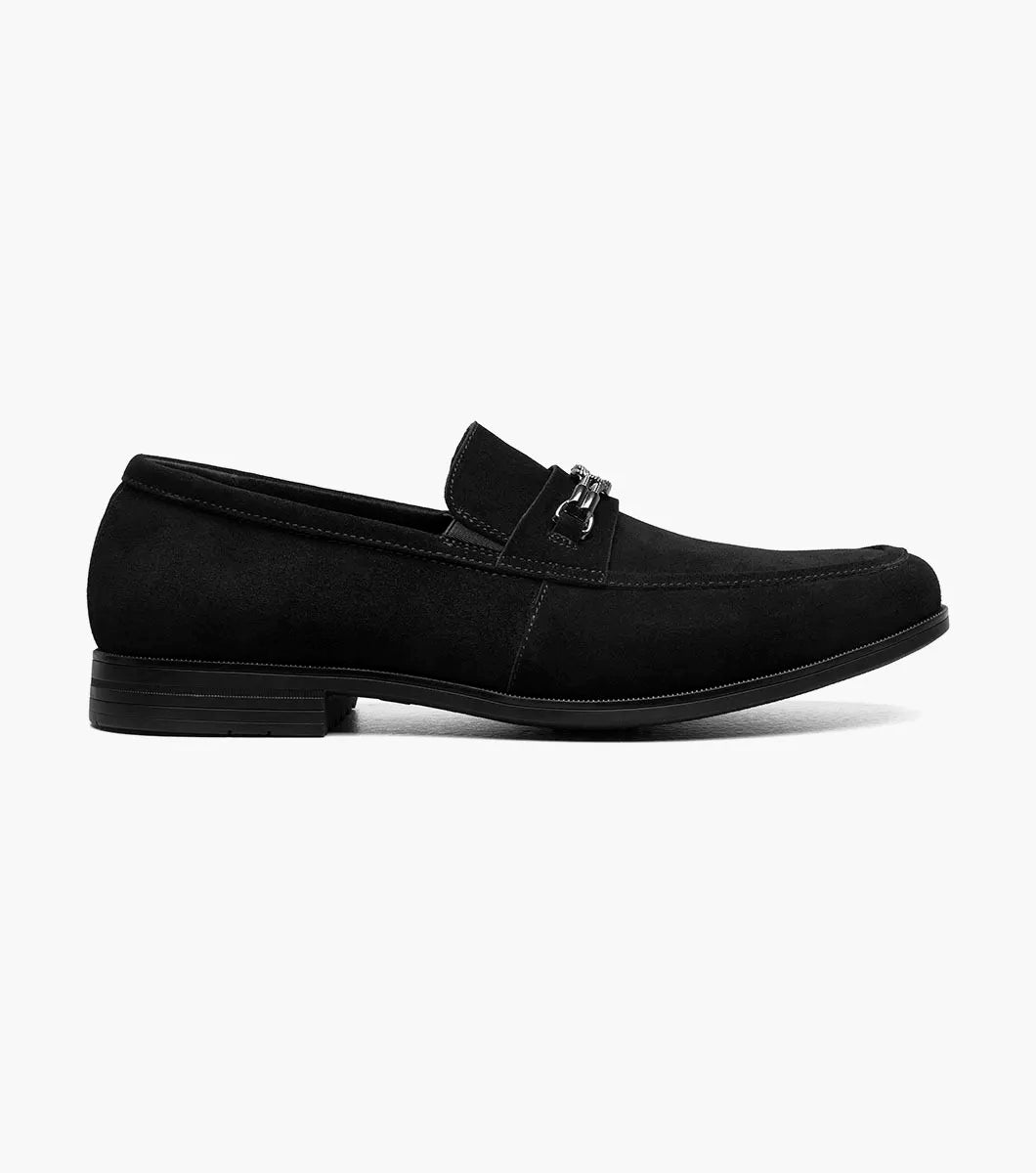 The STACY ADAMS Ravelle Moc Toe Bit Slip On in black suede features a low heel, metal bit on the vamp, anatomical arch support, and a red insole accent, shown against a white background.