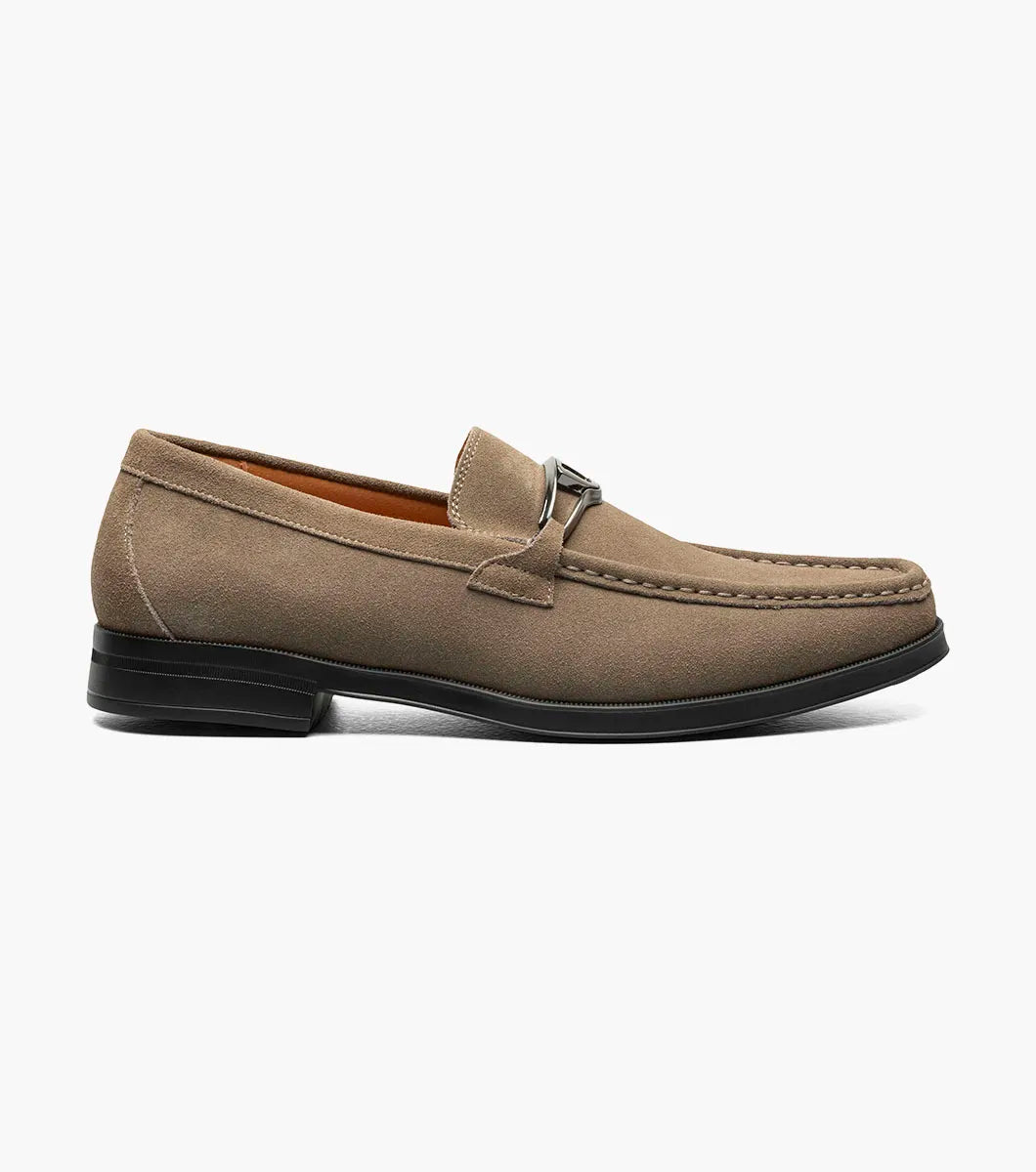 The Stacy Adams Palladian Moc Toe Slip On in Fossil Suede features a metal bit, visible stitching, and a black rubber sole for hybrid dress-casual comfort. Shown here is the men's shoe by STACY ADAMS on a white background.