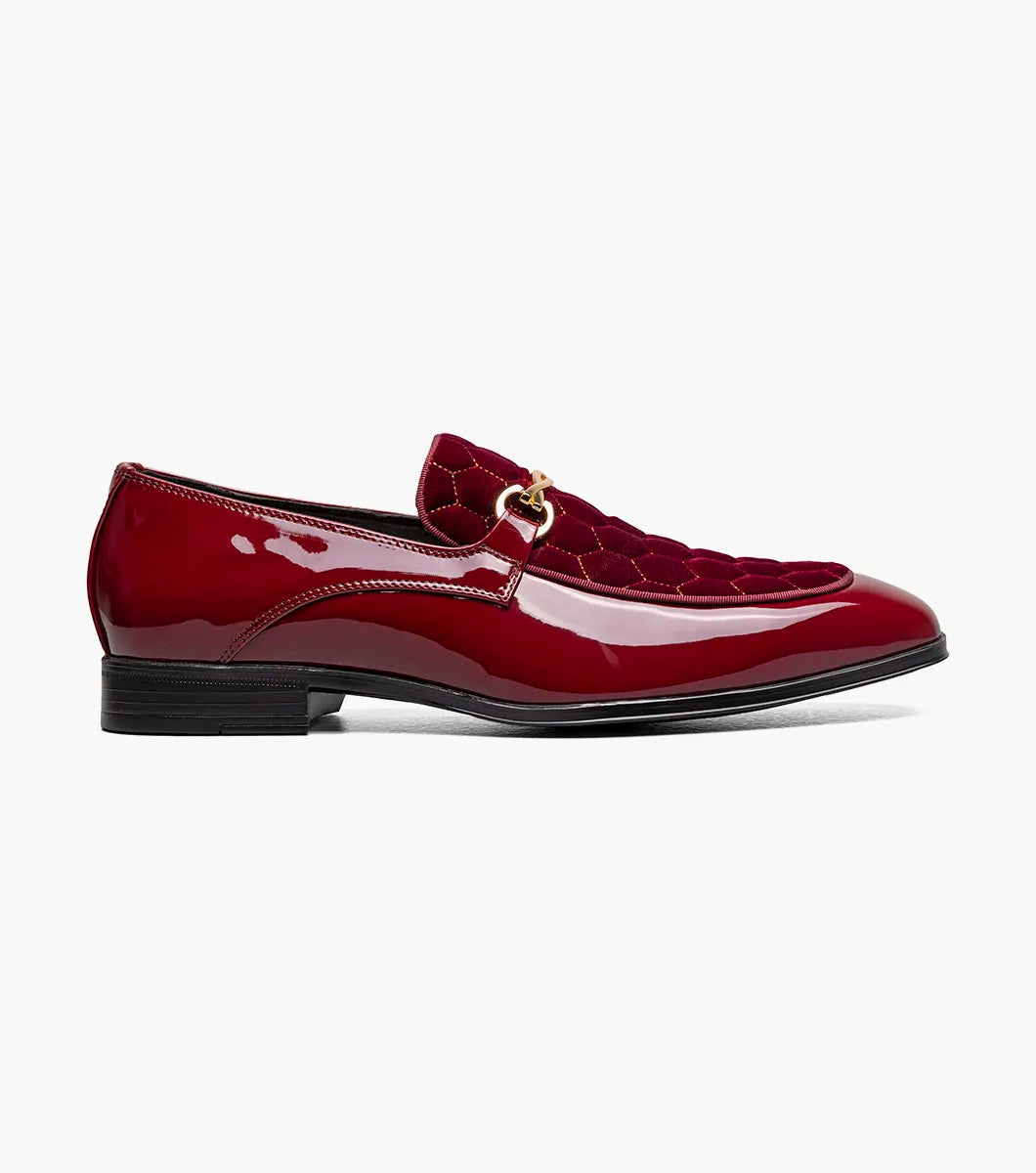 The STACY ADAMS Sprague Moc Toe Bit Slip On in burgundy (25732-601) features a glossy finish, gold buckle, hexagonal velvet-patterned upper, and a memory foam insole, shown against a white background.