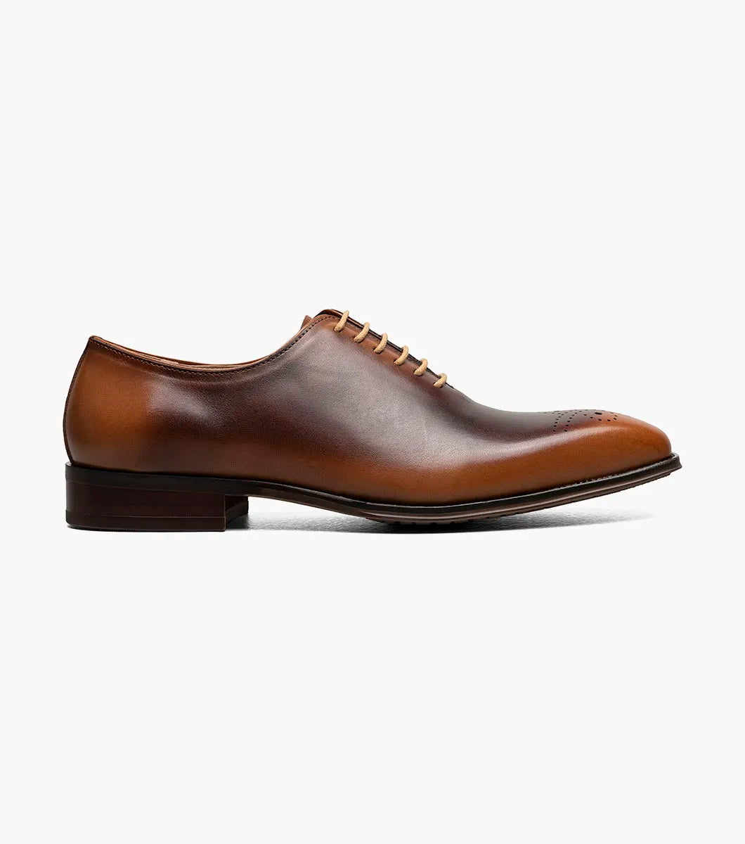 The STACY ADAMS Hallquist Plain Toe Oxford in toffee (25742-235) is a brown leather dress shoe with closed lacing, a low heel, toe perforations, and memory foam insole, shown against a white background.