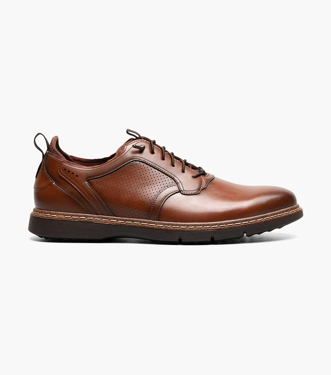 A single Stacy Adams Score Plain Toe Elastic Lace Up dress shoe in Cognac Smooth leather, featuring a textured side panel and a comfortable RedZone footbed, is shown at an angle on a white background.