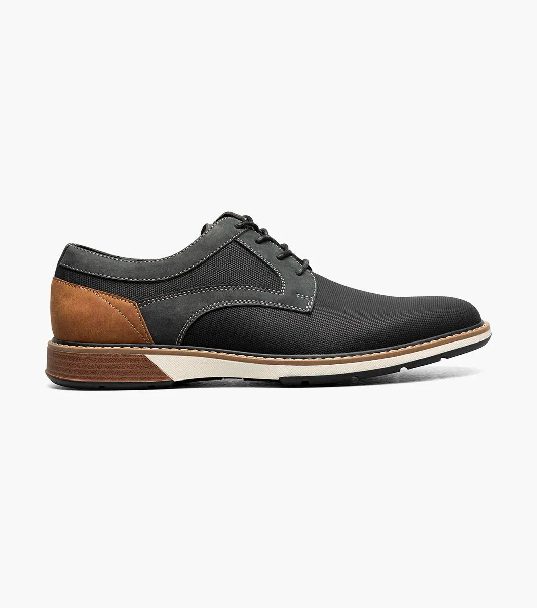 The Stacy Adams Phineas Plain Toe Oxford (25774-001) is a black lace-up oxford with textured material, gray stitching, a brown heel accent, and a cushioned insole for comfort, shown on a white background.