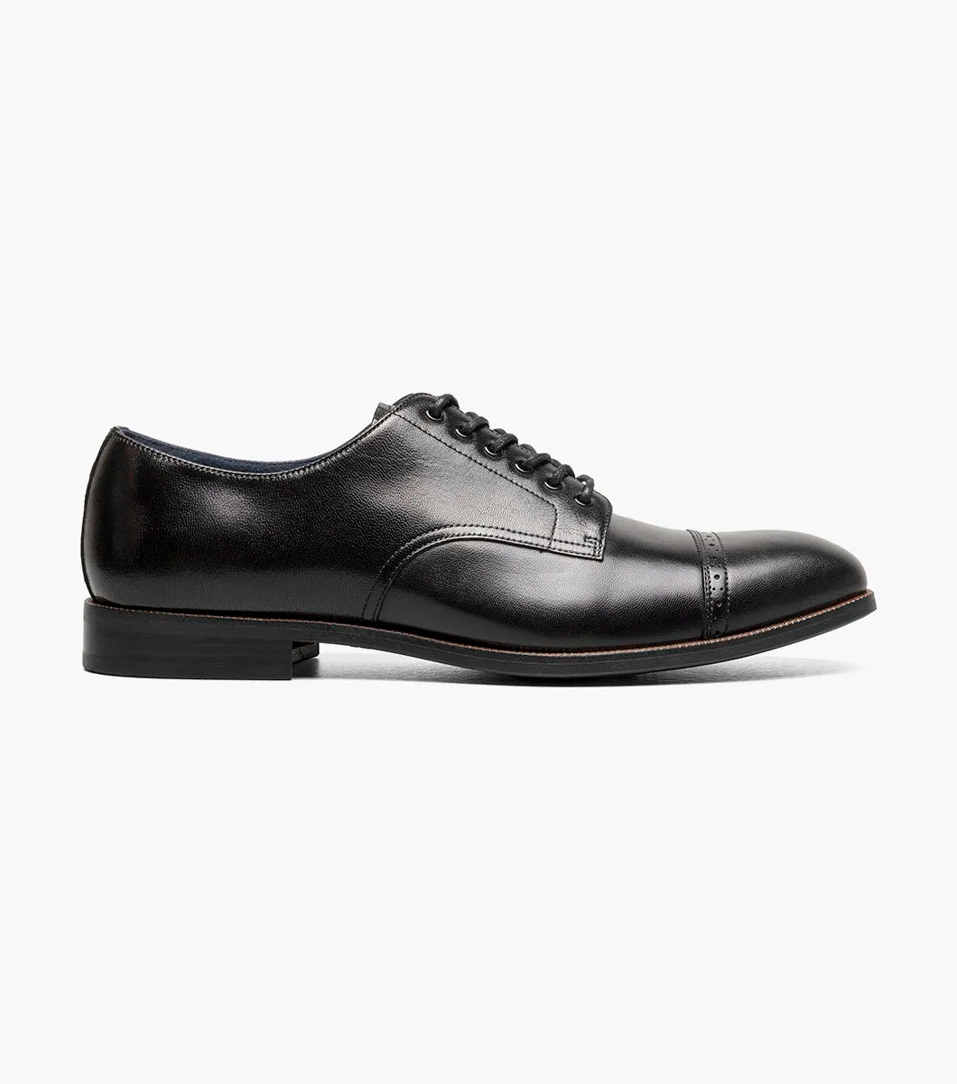 The STACY ADAMS William Cap Toe Oxford (Black, 25719-001) is a black burnished leather dress shoe with laces, a low heel, and comfortable stride, shown in profile against a white background.