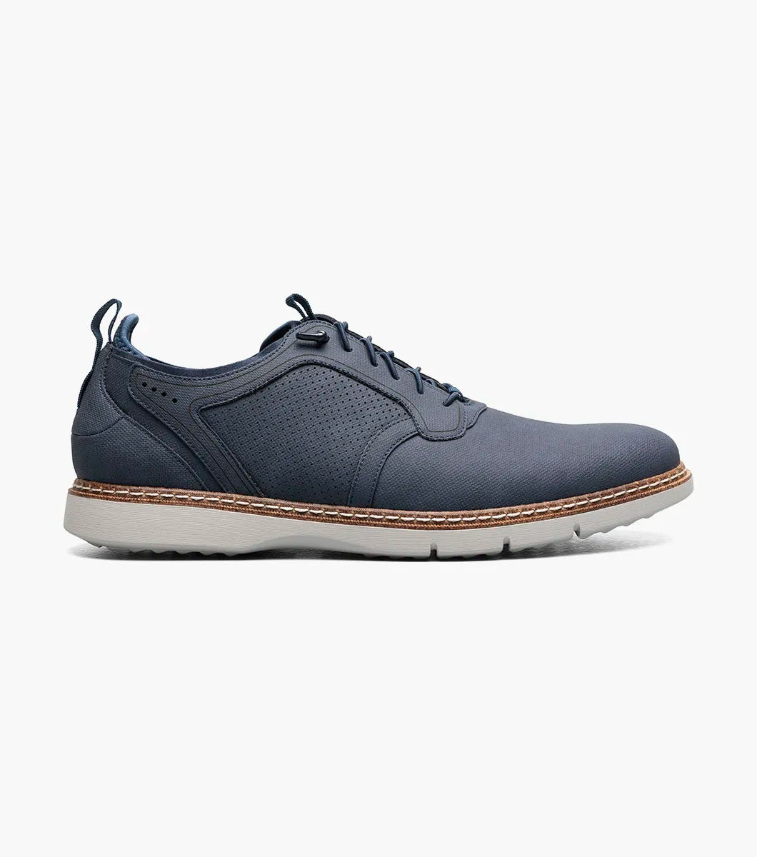 The STACY ADAMS Score Plain Toe Elastic Lace Up in navy (style 21538-410) is a blue dress shoe with elastic laces, featuring a perforated side panel, tan stitching, and a light-colored sole on a white background. It includes anatomical arch support for enhanced comfort.