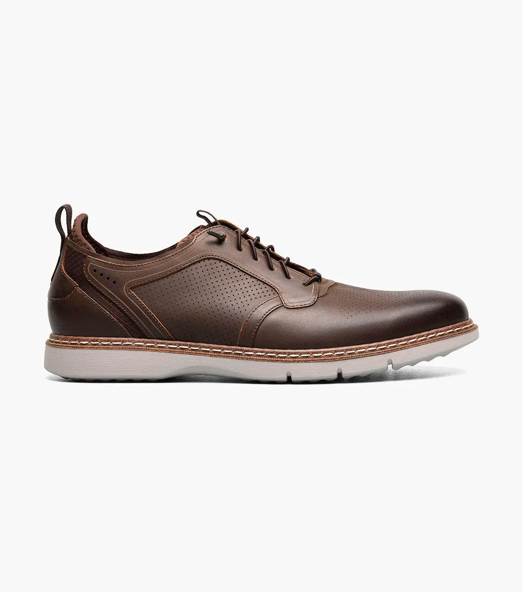 The Stacy Adams Sync Plain Toe Elastic Lace Up in brown features a leather upper, white sole, perforated details, and low-top design for all-day comfort. Shown on a plain white background. Brand: STACY ADAMS. Style: 25662-215.