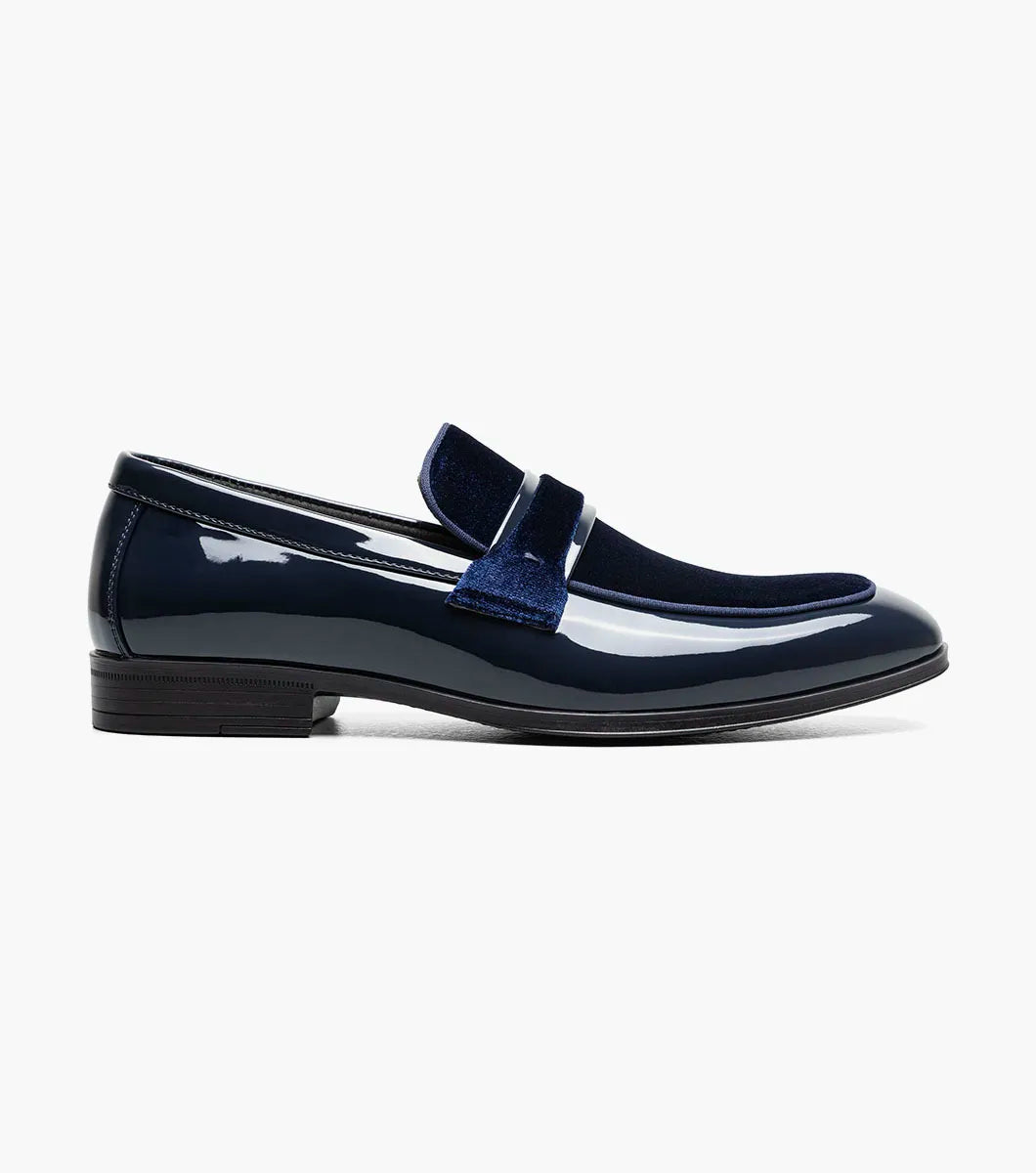 The Stacy Adams Spratley Moc Toe Saddle Slip On (25686-410) features shiny navy blue leather, a matching velour upper, cushioned insole, and low black heel. Displayed solo on a white background.